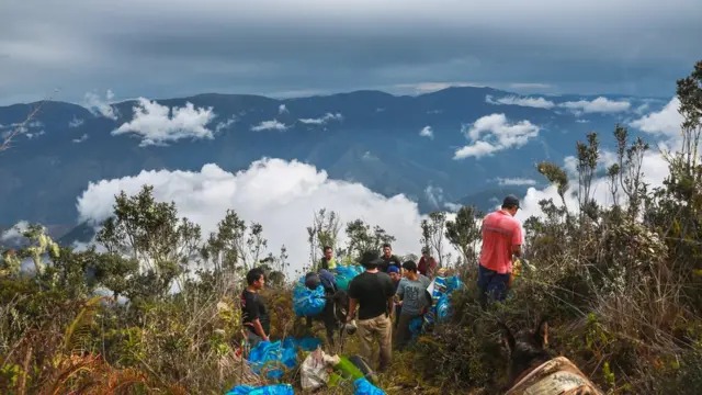 Expedition carrying gear along a ridge among the clouds
