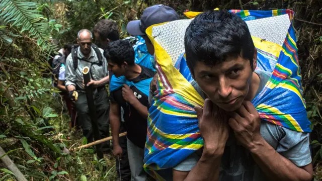 Line of porters advancing with gear through the dense forest