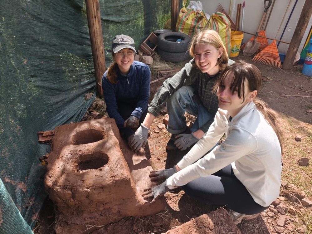 Viajeros participando en la construcción del horno de tierra para la pachamanca