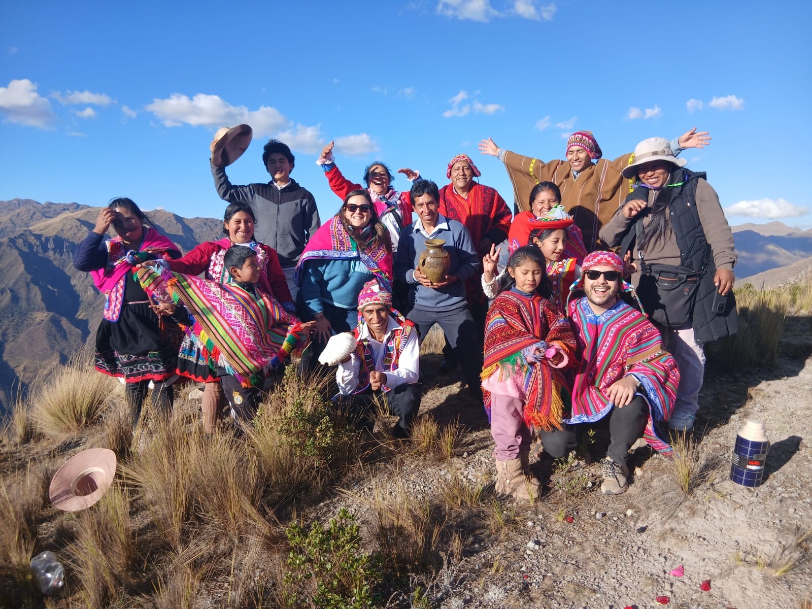 Grupo completo de viajantes e famílias da comunidade de Kallarayan celebrando no topo do Vale Sagrado, perto de Cusco, com uma oferenda à Pachamama