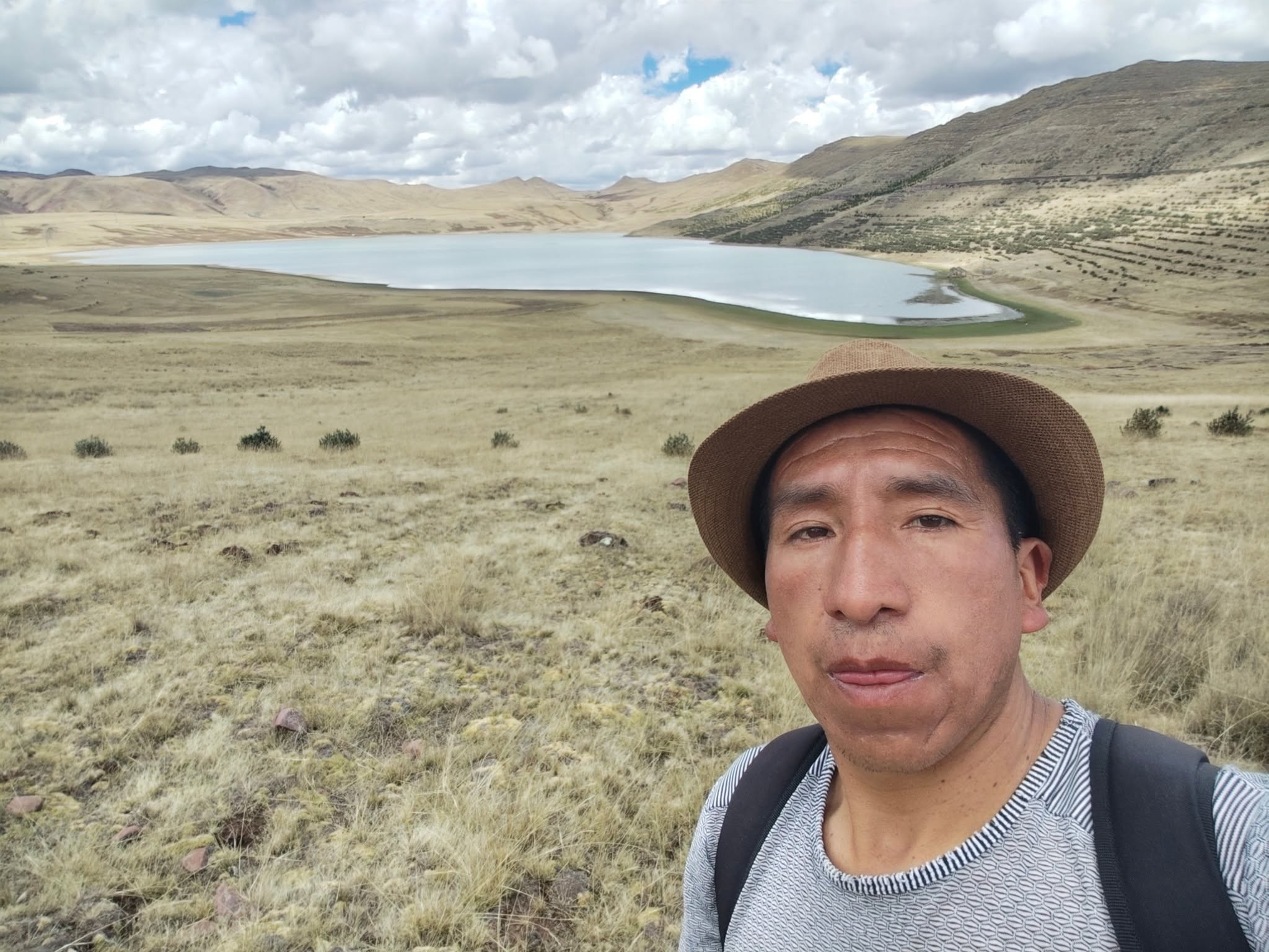 Guía local durante la caminata hacia Huchuy Cusco, con una laguna altoandina de fondo